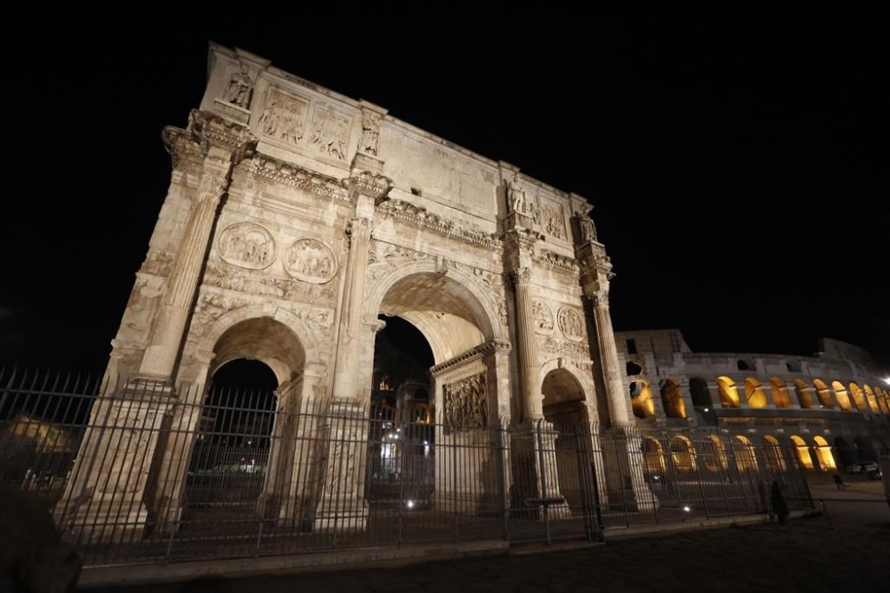 FILE -A view the Arch of Constantine, and the Colosseum, background right, on the occasion of the unveiling of new lightning, in Rome, July 17, 2020. (AP Photo/Riccardo De Luca, File)