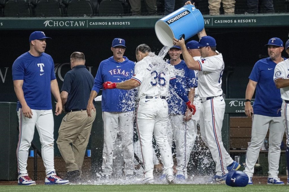 Texas Rangers' Wyatt Langford (36) is doused with water by assistant hitting coach Seth Conner after hitting a walk-off grand slam off New York Yankees relief pitcher Clay Holmes during the ninth inning of a baseball game Tuesday, Sept. 3, 2024, in Arlington, Texas. Leody Taveras, Josh Smith and Marcus Semien scored on the play. (AP Photo/Jeffrey McWhorter)