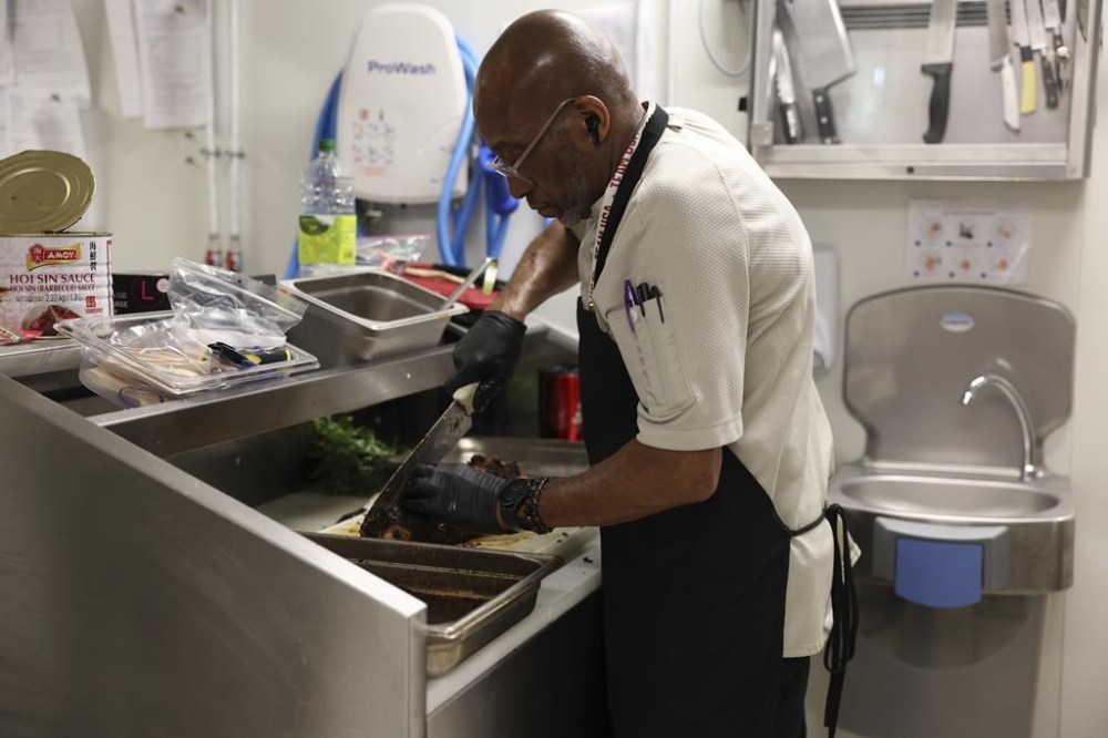 Kevin Oakes, cuts a rosemary pork loin with rosemary au jus in the kitchen of the United States Olympic and Paralympic Committee's High Performance Center during the Paralympic Games in Paris on Saturday, Aug. 31, 2024. Oakes has worked with the USOPC in Colorado Springs for three years. Oaks said that coming to Paris for the 2024 Olympic and Paralympic Games was his first time out of the country.