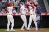 Los Angeles Angels' Mickey Moniak, second fro left, is congratulated by Anthony Rendon and Nolan Schanuel, second from left, after hitting a three-run home run as Los Angeles Dodgers catcher Austin Barnes stands by during the first inning of a baseball game, Wednesday, Sept. 4, 2024, in Anaheim, Calif. (AP Photo/Mark J. Terrill)