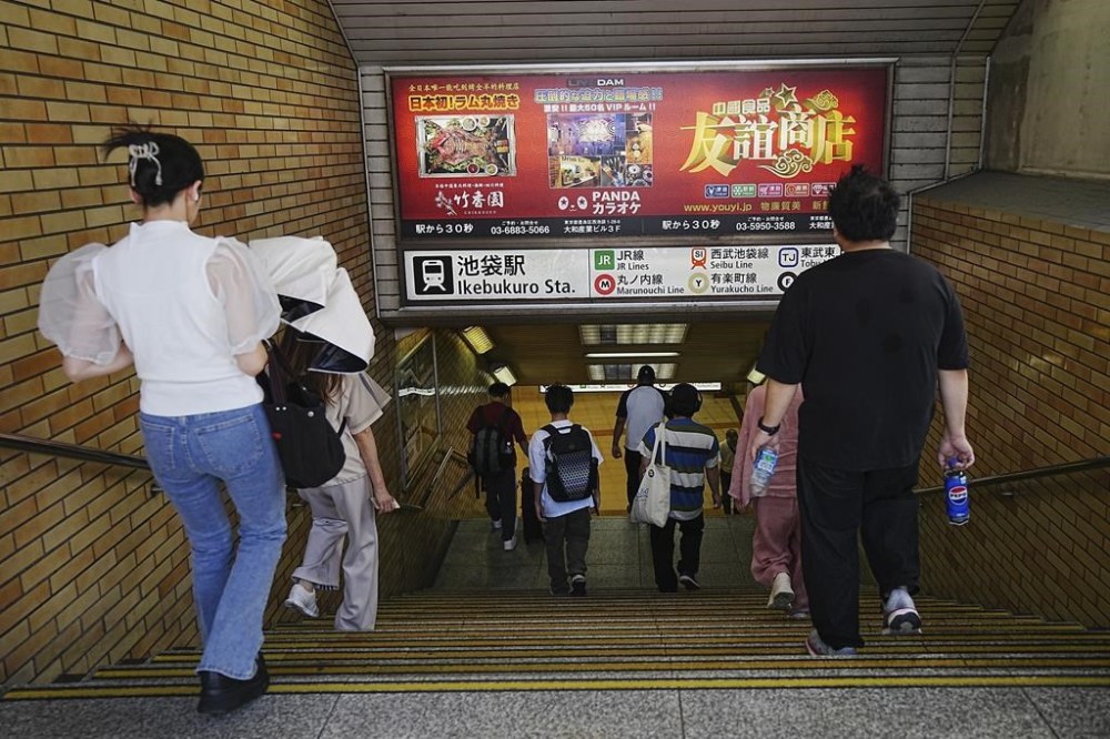 Commuters walks past advertisements of Chinese restaurant and karaoke which are popular among Chinese living in Japan at Ikebukuro station Wednesday, Sept. 4, 2024, in Tokyo. (AP Photo/Eugene Hoshiko)