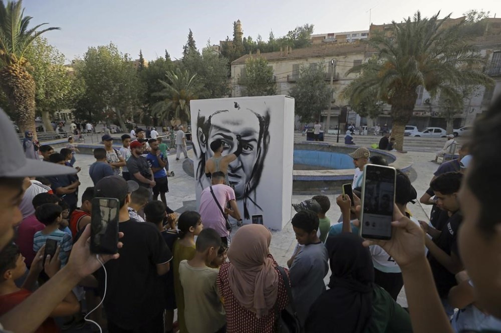 An artist paints a portrait of Algerian boxer Imane Khelif before the women's 66-kg boxing Olympic final match in Bibane Mesbah, near Tiaret, Algeria, Friday , Aug. 9, 2024. (AP Photo/Anis Belghoul)