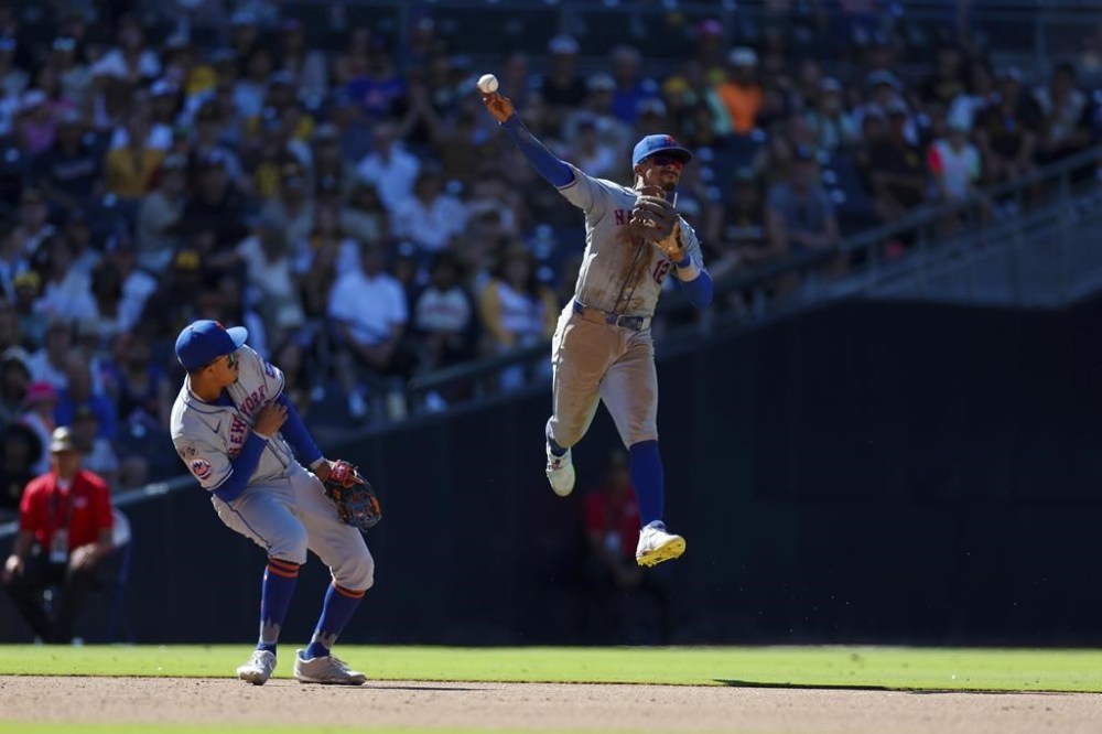 New York Mets shortstop Francisco Lindor, right, makes a jumping throw on a single hit by San Diego Padres' Xander Bogaerts during the eighth inning of a baseball game, Sunday, Aug. 25, 2024, in San Diego. (AP Photo/Brandon Sloter)
