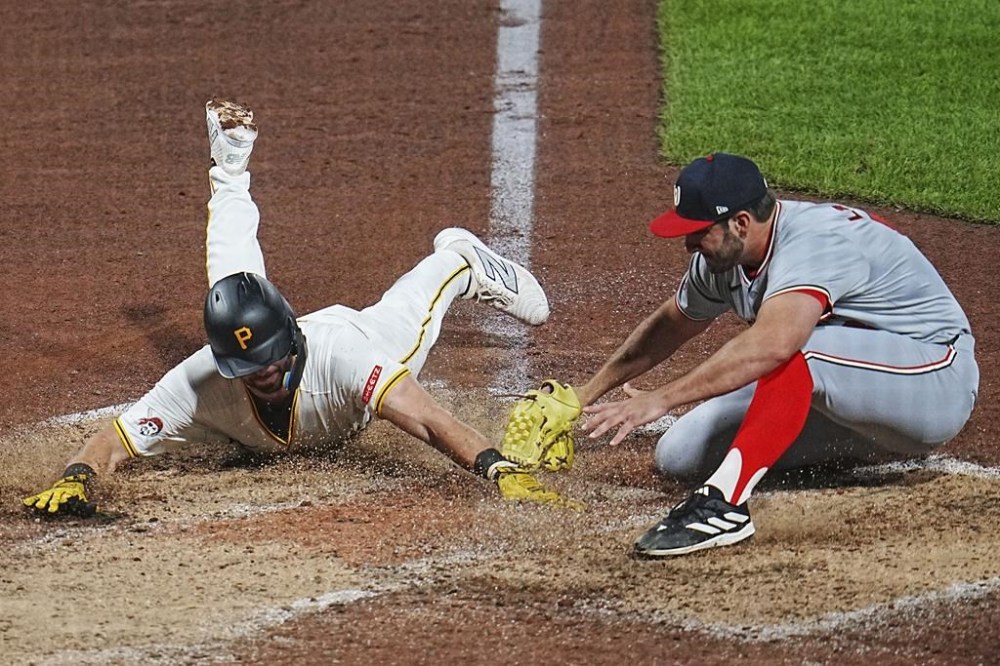Pittsburgh Pirates' Jared Triolo, left, scores on a wild pitch by Washington Nationals relief pitcher Joe La Sorsa, right, during the sixth inning of a baseball game in Pittsburgh, Thursday, Sept. 5, 2024. (AP Photo/Gene J. Puskar)