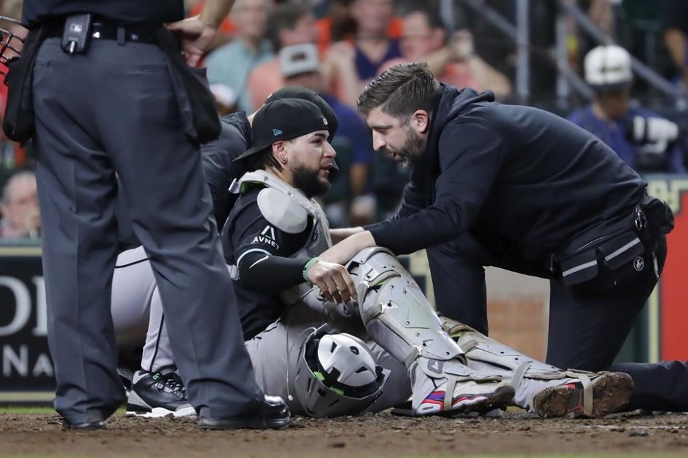 Arizona Diamondbacks catcher Jose Herrera, center, is tended to by trainers after being hit in the head on the back swing by Houston Astros' Kyle Tucker during the fifth inning of a baseball game, Friday, Sept. 6, 2024, in Houston. Herrera left the game after the incident. (AP Photo/Michael Wyke)
