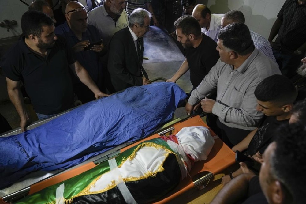 Palestinian mourners gather around the covered bodies of Turkish-American Aysenur Ezgi Eygi, 26, and Bana Bakr, 13, at a morgue in Nablus, West Bank, Saturday, Sept. 7, 2024. Witnesses said Eygi, was fatally shot by Israeli forces in a moment of calm after clashes between Palestinians and Israeli forces near Nablus on Friday. Bakr was also killed by Israeli fire the Palestinian health ministry said, while the Israeli army said they were reviewing the incident which happened during clashes between Palestinians and Israeli nationals in an area south of Nablus. (AP Photo/Majdi Mohammed)