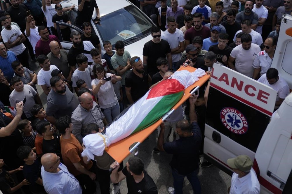 Mourners carry the body of Palestinian girl Bana Bakr, 13, into the family house during her funeral in the West Bank village of Qaryut, south of Nablus, Saturday, Sept. 7, 2024. Bakr was killed by Israeli fire, the Palestinian health ministry said. The Israeli army said they were reviewing the incident. (AP Photo/Nasser Nasser)