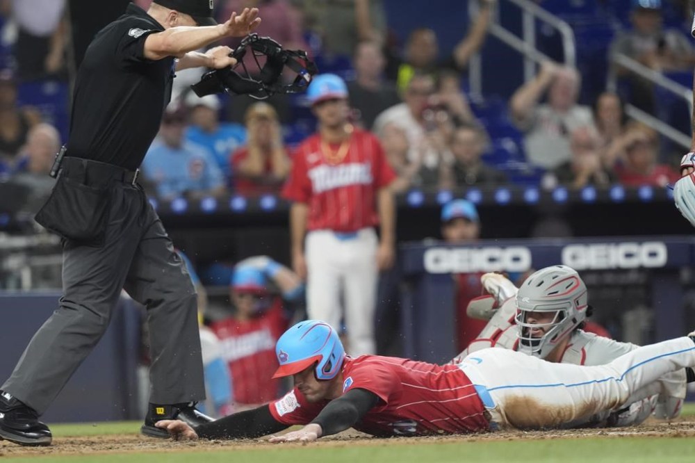 Miami Marlins' Nick Fortes scores as Philadelphia Phillies catcher Garrett Stubbs (21) is late with the tag on a throwing error by shortstop Trea Turner during the seventh inning of a baseball game, Saturday, Sept. 7, 2024, in Miami. (AP Photo/Marta Lavandier)