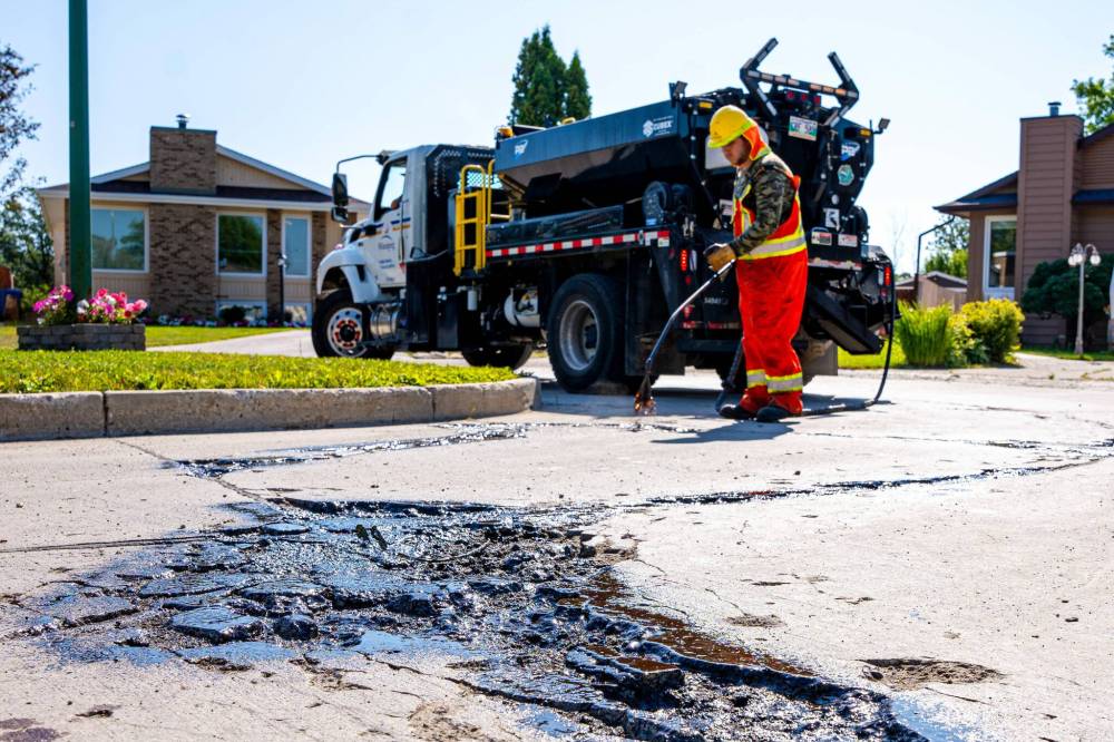 City crews repair street damage on Julien Place in St. Norbert Tuesday, a day after the Free Press reached out about a pothole first reported to the city in 2022. Resident Vic Hiebert took matters into his own hands, filling the hole with concrete this summer. (Nic Adam / Free Press)
