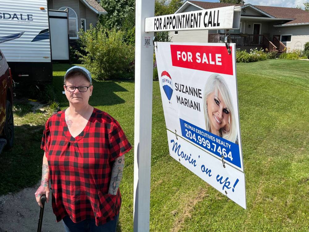 Roseanne Milburn stands in front of the ’for sale' sign at her home in Elie, MB. Milburn and her husband, Dan, are moving to Alberta, hoping she‘ll be fast-tracked for a double knee replacement, a procedure she has been waiting on for six years in Manitoba. (Supplied)