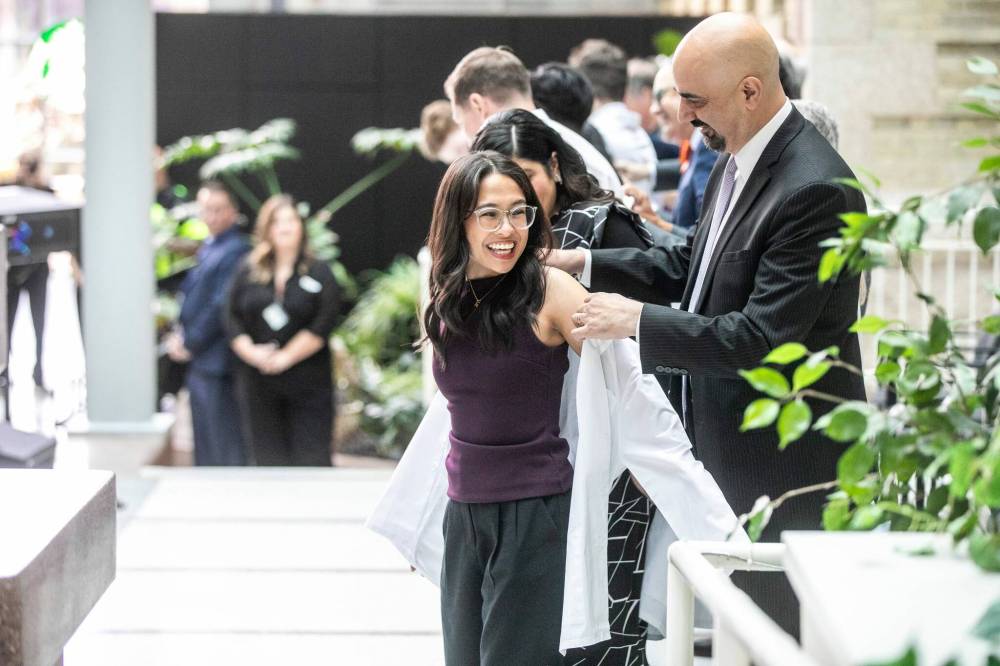 MIKAELA MACKENZIE / FREE PRESS
WRHA CEO Mike Nader cloaks Allison Afable during Wednesday’s white-coat ceremony for the newest University of Manitoba medical class.