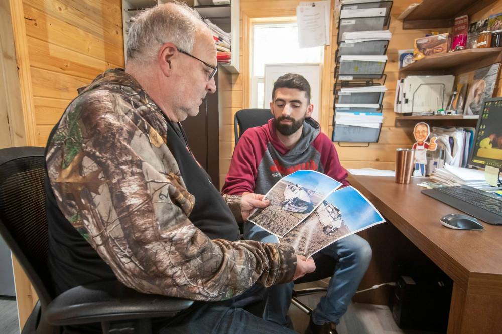 Danny Kleinsasser (left) with his son Isaiah looks at photos of the truck he was driving that was hit by a gravel truck in March 2024. (Brook Jones / Free Press)