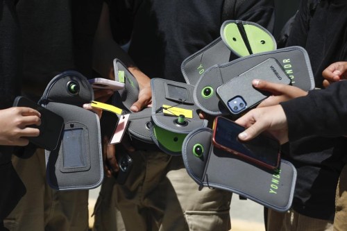 FILE - A student uses their cell phone after unlocking the pouch that secures it from use during the school day at Bayside Academy, Aug. 16, 2024, in San Mateo, Calif. (Lea Suzuki/San Francisco Chronicle via AP, File)