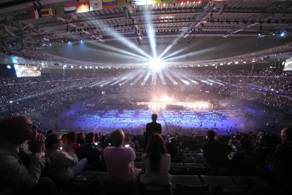 Spectators attend the closing ceremony of the 2024 Paralympics under the rain, Sunday, Sept. 8, 2024, in Paris, France. (AP Photo/Christophe Ena)