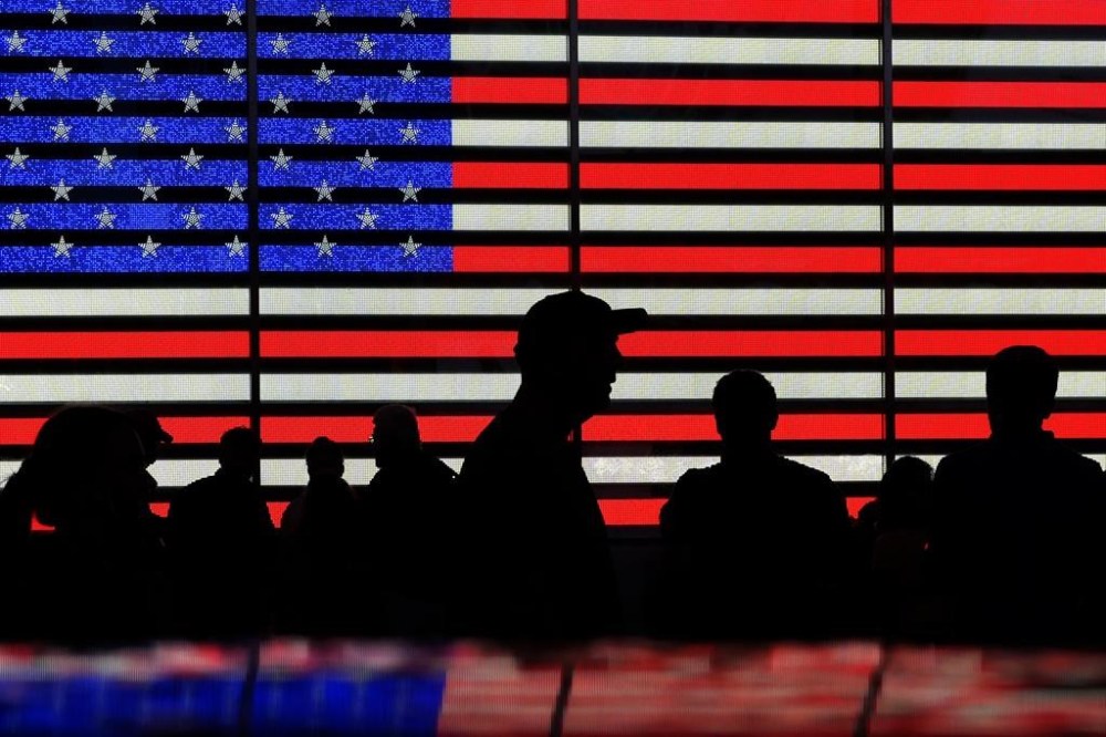FILE - People gather near an electronic display of an American flag in Times Square in New York on Aug. 9, 2024. (AP Photo/Pamela Smith, File)