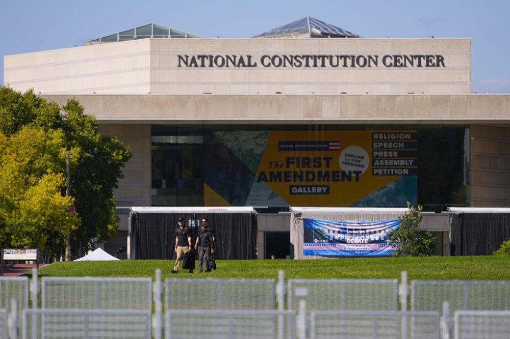 People are seen walking on the lawn of the National Constitution Center, the site of tonight's presidential debate between Republican presidential nominee former President Donald Trump and Democratic presidential nominee Vice President Kamala Harris, Tuesday, Sept. 10, 2024, in Philadelphia. (AP Photo/Matt Slocum)