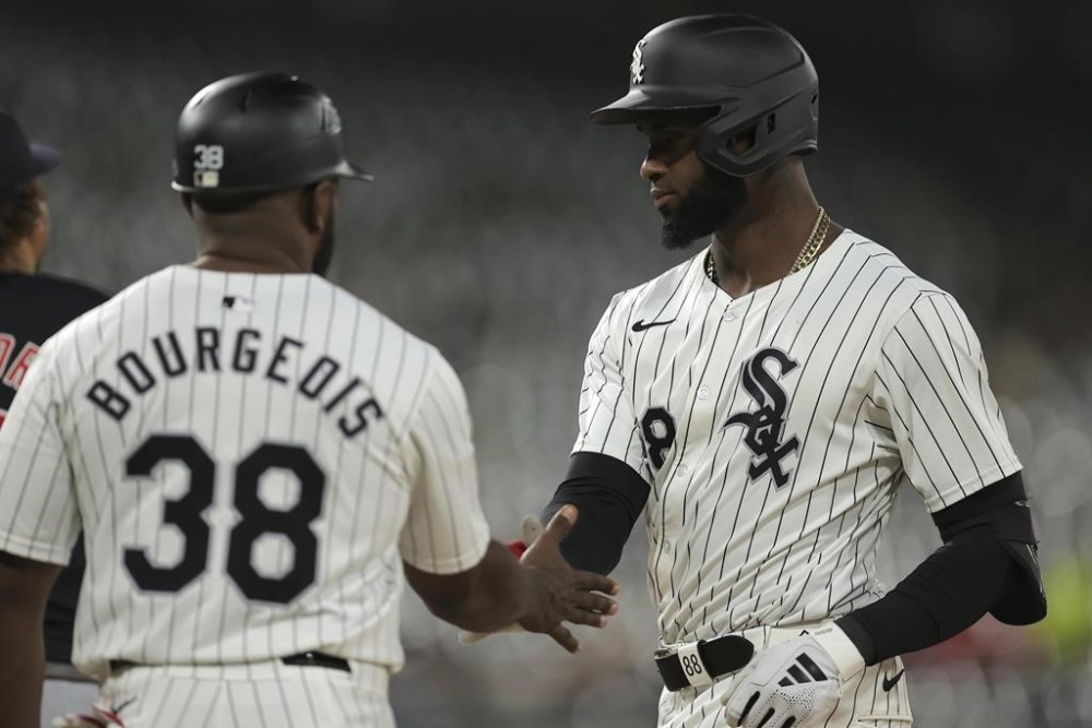 Chicago White Sox's Luis Robert Jr. high fives first base coach Jason Bourgeois after hitting a single during the third inning of a baseball game against the Cleveland Guardians, Tuesday, Sept. 10, 2024, in Chicago. (AP Photo/Melissa Tamez)
