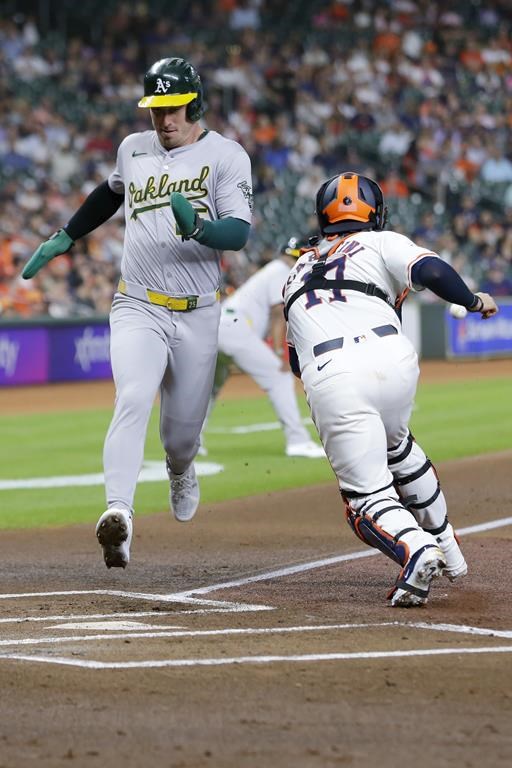 Oakland Athletics' Brent Rooker, left, scores on the sacrifice fly by Shea Langeliers as Houston Astros catcher Victor Caratini reaches for the ball during the first inning of a baseball game, Tuesday, Sept. 10, 2024, in Houston. (AP Photo/Michael Wyke)