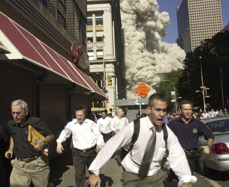 FILE - People run from a collapsing World Trade Center tower in New York, Sept. 11, 2001. (AP Photo/Suzanne Plunkett, File)