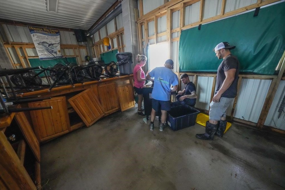 The Pellegrin family cleans up the damage from a storm surge in their family's camp in the aftermath of Hurricane Francine in Cocodrie, La., Thursday, Sept. 12, 2024. (AP Photo/Gerald Herbert)
