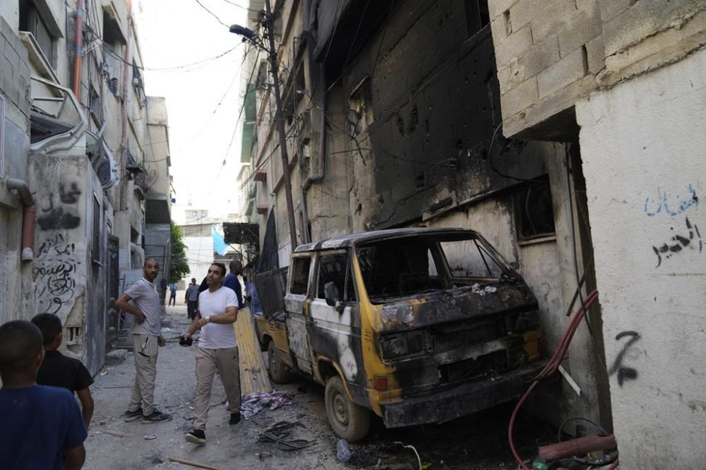 Palestinian refugees inspect a burnt vehicle in a West Bank refugee camp in Tulkarem, during an Israeli army operation in Tulkarem, Thursday, Sept. 12, 2024. (AP Photo/Nasser Nasser)