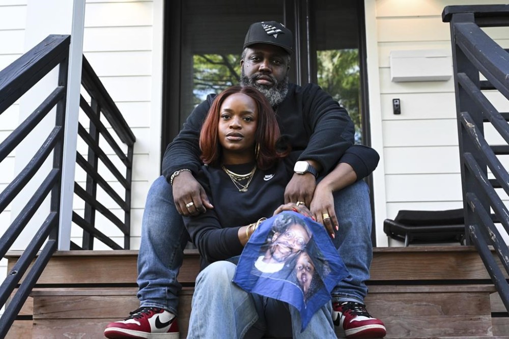 Reggie Cunningham, top, and his wife Ferguson activist Brittany Packnett-Cunningham pose for an image while holding a handkerchief with picture of her father Rev. Ronald Packnett and Brittany, Saturday, Sep. 7, 2024, in Mount Rainier, Md. (AP Photo/Terrance Williams)