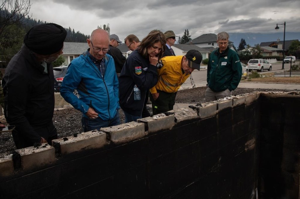 Jasper Mayor Richard Ireland, second left in blue, looks at what is left of his home of 67 years with federal Minister of Emergency Preparedness Harjit Sajjan, left to right, Alberta Premier Danielle Smith, and Minister of Forestry and Parks. The municipality of Jasper, Alta. is ending its state of local emergency on Sunday, less than two months after wildfire destroyed a third of the town. THE CANADIAN PRESS/Amber Bracken
