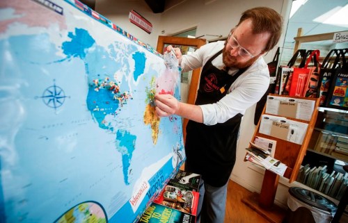 Michael Bumsted, who owns the independent bookstore Whodunit Mystery Bookstore with his mother Wendy, places a pin in Europe where his most recent foreign sale happened in their store Wednesday, Sept. 4, 2024 in Winnipeg. THE CANADIAN PRESS/John Woods