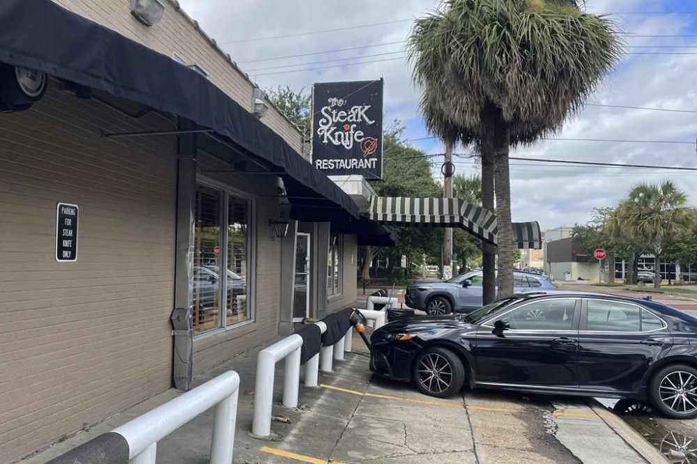 Floor mats from inside The Steak Knife, a New Orleans restaurant, are hung out to dry on parking barriers after Hurricane Francine passed over the city the night before, Thursday, Sept. 12, 2024. (AP Photo/Brett Martel)