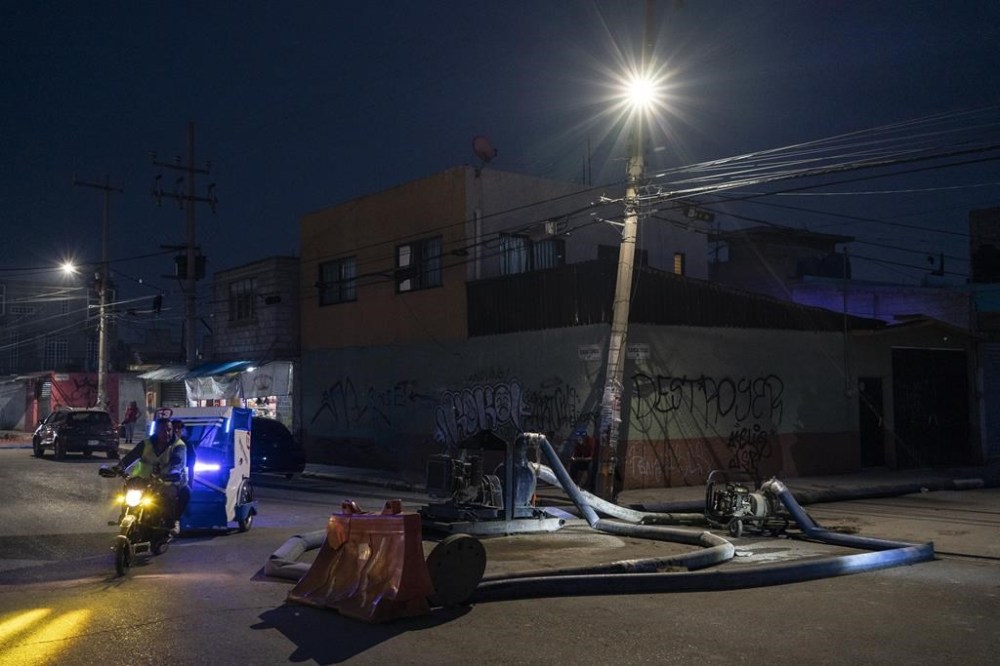 Hoses pump away sewage-infused floodwaters in Valle de Chalco, State of Mexico, lat Monday, Sept. 9, 2024. (AP Photo/Felix Marquez)
