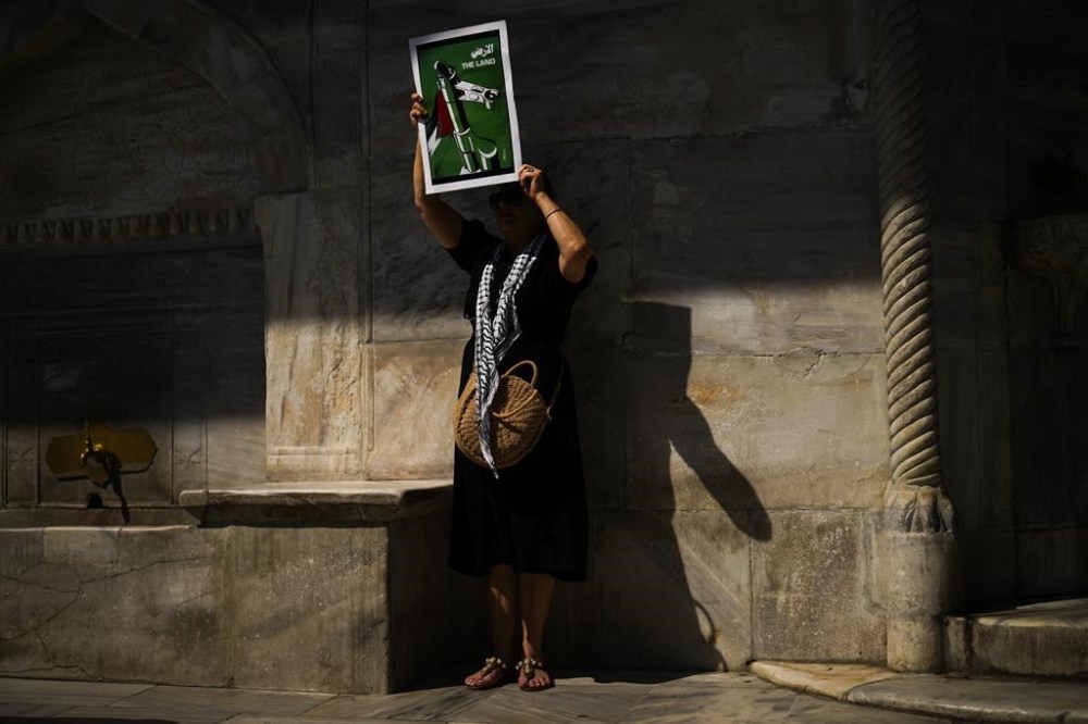 A woman holds up a poster that reads: