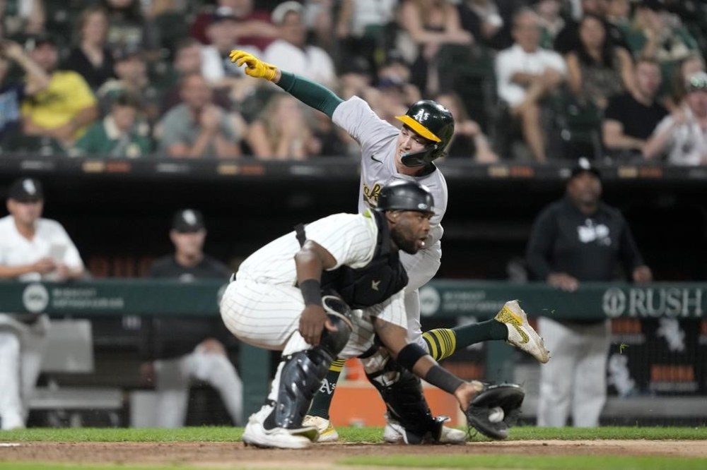 Oakland Athletics' Jacob Wilson, top, scores behind Chicago White Sox catcher Chuckie Robinson during the sixth inning of a baseball game Saturday, Sept. 14, 2024, in Chicago. (AP Photo/Charles Rex Arbogast)