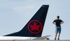 A person watches as an Air Canada plane lands at Montreal-Pierre Elliott Trudeau International Airport in Montreal, Friday, Sept. 13, 2024. THE CANADIAN PRESS/Christinne Muschi