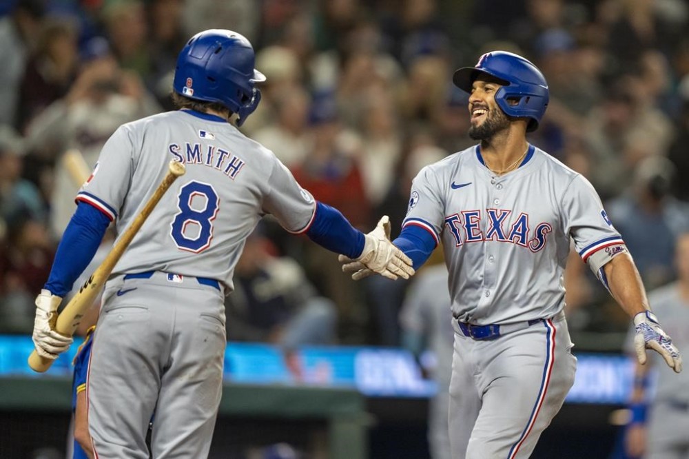 Texas Rangers' Marcus Semien, right, celebrates with Josh Smith after hitting a two-run home run during the fifth inning of a baseball game against the Seattle Mariners, Saturday, Sept. 14, 2024, in Seattle. (AP Photo/Stephen Brashear)