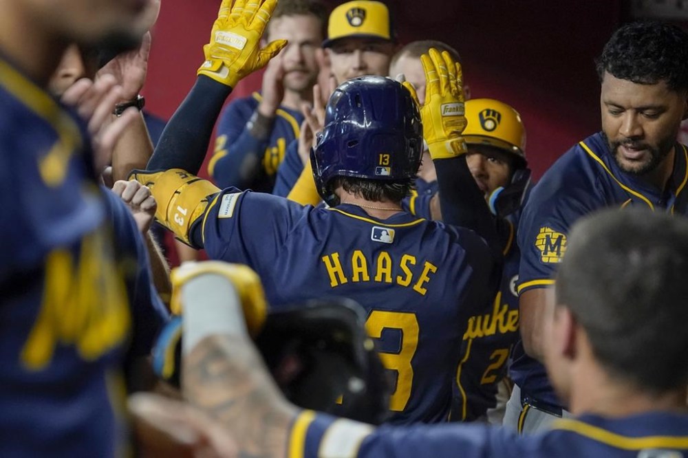Milwaukee Brewers' Eric Haase, center, gets high-fives after hitting a home run against the Arizona Diamondbacks during the sixth inning of a baseball game, Sunday, Sept. 15, 2024, in Phoenix. (AP Photo/Darryl Webb)