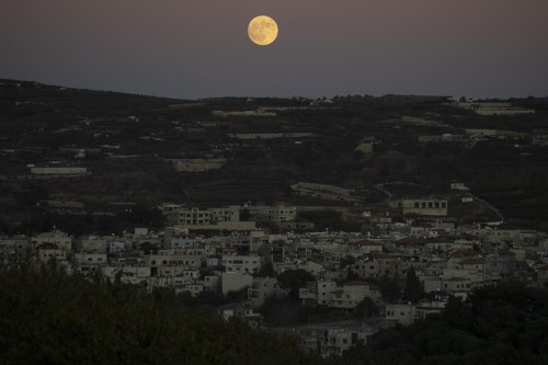 The supermoon rises behind the houses in Mas'ade, a village in the Israeli-annexed Golan Heights, Tuesday, Sept. 17, 2024. (AP Photo/Leo Correa)
