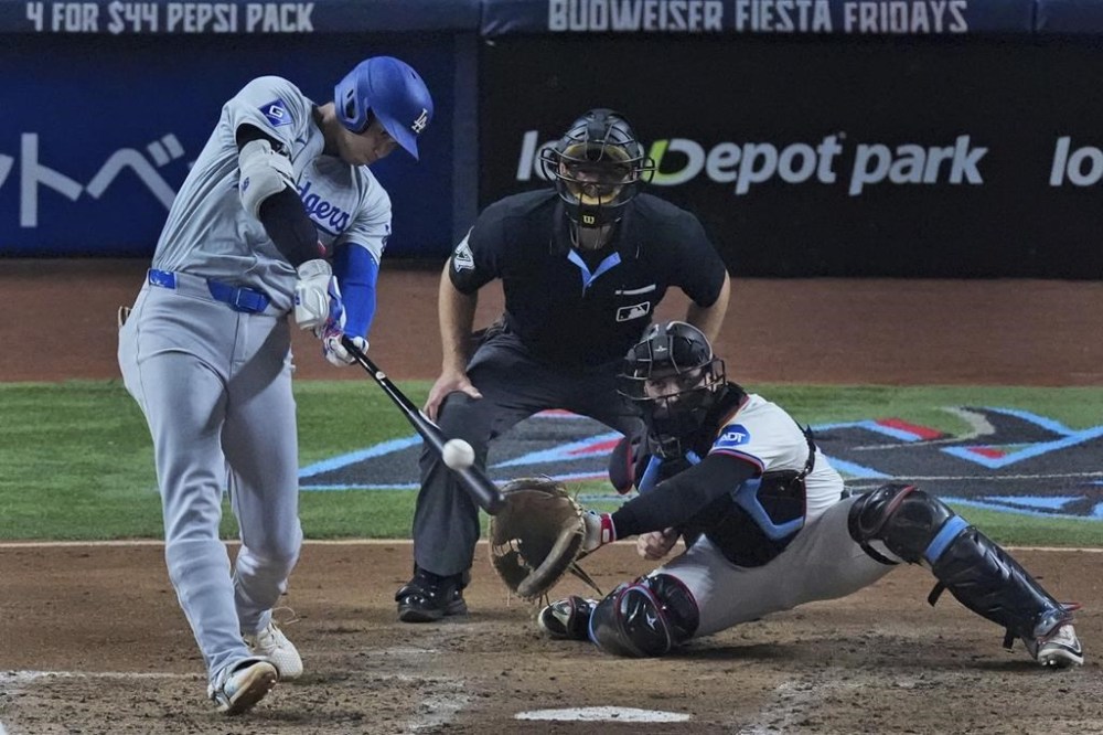 Los Angeles Dodgers' Shohei Ohtani, of Japan, hits a home run scoring Hunter Feduccia during the third inning of a baseball game against the Miami Marlins, Tuesday, Sept. 17, 2024, in Miami. (AP Photo/Wilfredo Lee)
