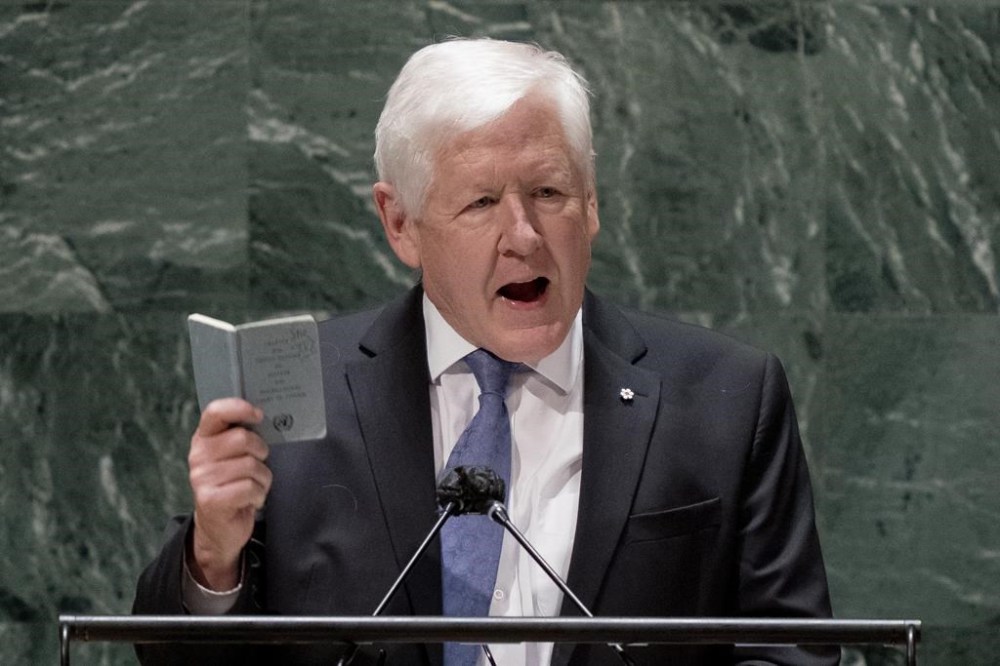 Bob Rae, ambassador of Canada to the United Nations, speaks while holding a copy of the United Nations charter at the general assembly hall, Wednesday, Feb. 23, 2022, at United Nations Headquarters. Canada abstained today in a high-profile United Nations vote demanding that Israel end its