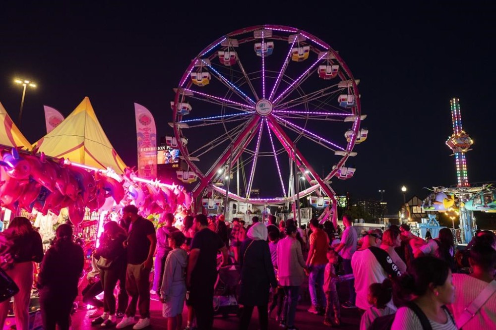 People walk past the ferris wheel the Canadian National Exhibition (CNE) in Toronto, Thursday, Aug. 29, 2024. The Canadian National Exhibition says big Labour Day long weekend crowds helped lift attendance to 1.49 million visitors during this year's festivities. THE CANADIAN PRESS/Paige Taylor White