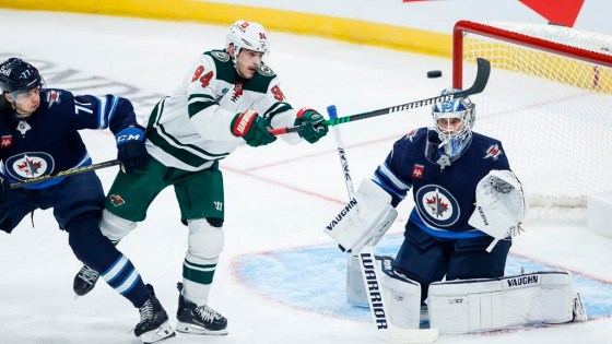 Winnipeg Jets' Tyrel Bauer (77) defends as Minnesota Wild's Jakub Lauko (94) attempts to tip the puck past Jets goaltender Kaapo Kahkonen on Sept. 21, 2024. (John Woods / The Canadian Press files)