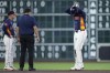 Houston Astros' Yordan Alvarez, right, tests his right leg for manager Joe Espada, left, and a member of the athletic training staff after injuring himself while sliding into second base on a double during the third inning of a baseball game against the Los Angeles Angels, Sunday, Sept. 22, 2024, in Houston. (AP Photo/Kevin M. Cox)