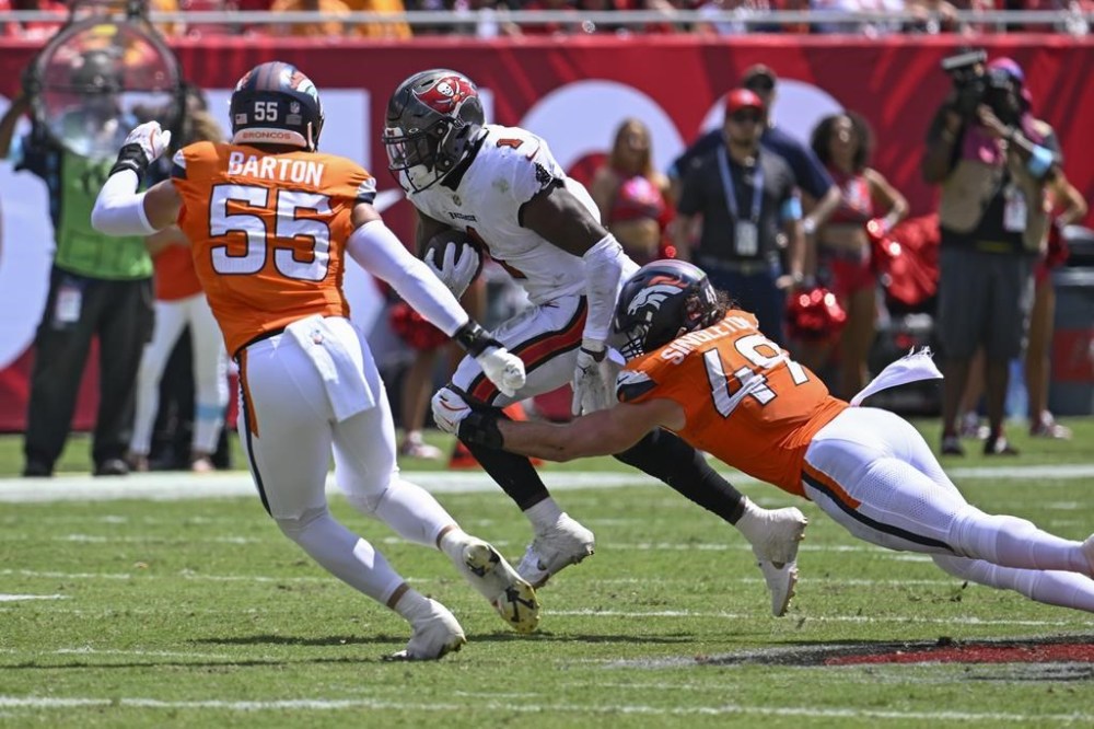 Tampa Bay Buccaneers running back Rachaad White, center, gains yardage against Denver Broncos linebacker Alex Singleton (49) and linebacker Cody Barton (55) during the first half of an NFL football game, in Tampa, Fla. on Sunday, Sept. 22, 2024. (AP Photo/Jason Behnken)