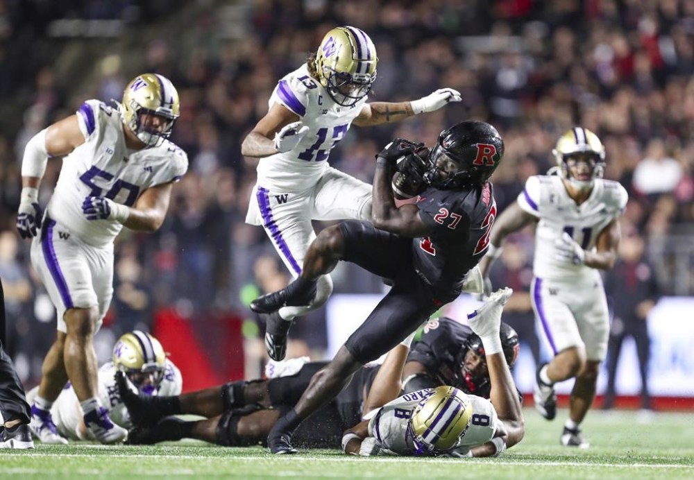 Rutgers running back Samuel Brown V (27) breaks a tackle attempt by Washington safety Cameron Broussard (8), keeps his balance and runs for a 37-yard touchdown during the fourth quarter of an NCAA football game, Friday, Sept. 27 2024, in Piscataway, N.J. (Andrew Mills/NJ Advance Media via AP)