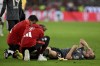 Munich's Harry Kane gets assistance as he lies on the pitch during the German Bundesliga soccer match between Bayern Munich and Leverkusen at the Allianz Arena in Munich, Germany, Saturday, Sept. 28, 2024. (Sven Hoppe/dpa via AP)