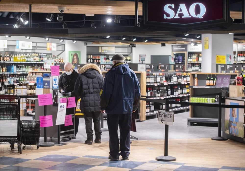 The provincial Crown corporation in charge of liquor sales in Quebec is confirming that a computer error resulted in all its products being temporarily listed at 30 per cent off on its website. People wait to enter a SAQ outlet in Montreal, Tuesday, January 18, 2022. THE CANADIAN PRESS/Graham Hughes