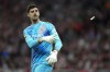 Real Madrid's goalkeeper Thibaut Courtois throws off the pitch a lighter, previously thrown by Atletico Madrid fans, during the La Liga soccer match between Atletico Madrid and Real Madrid at the Metropolitano stadium in Madrid, Spain, Sunday, Sept. 29, 2024. (AP Photo/Bernat Armangue)