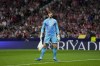 Real Madrid's goalkeeper Thibaut Courtois holds a bag, thrown by Atletico Madrid fans, during the La Liga soccer match between Atletico Madrid and Real Madrid at the Metropolitano stadium in Madrid, Spain, Sunday, Sept. 29, 2024. (AP Photo/Bernat Armangue)