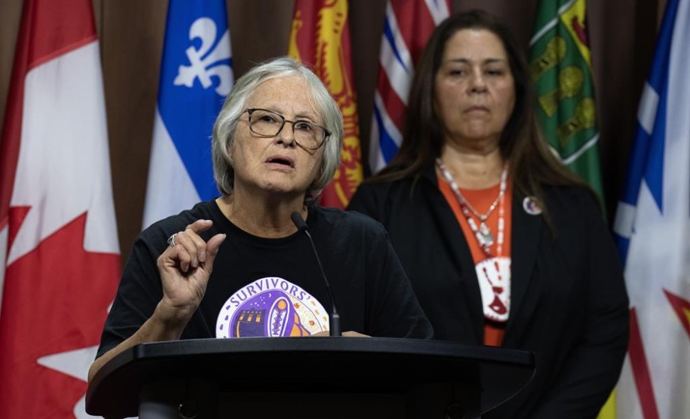 The Survivors' Secretariat Executive Lead Laura Arndt, right, looks on as survivor of the Mohawk Institute and Secretariat board member Roberta Hill speaks during a news conference on Parliament Hill, in Ottawa, Monday, Sept. 30, 2024. THE CANADIAN PRESS/Adrian Wyld