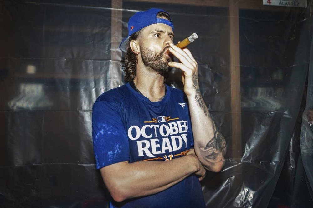 A New York Mets. player smokes a cigar in the locker room after clinching a playoff berth with a victory in the first baseball game of a doubleheader against the Atlanta Braves, Monday, Sept. 30, 2024, in Atlanta. (AP Photo/Jason Allen)