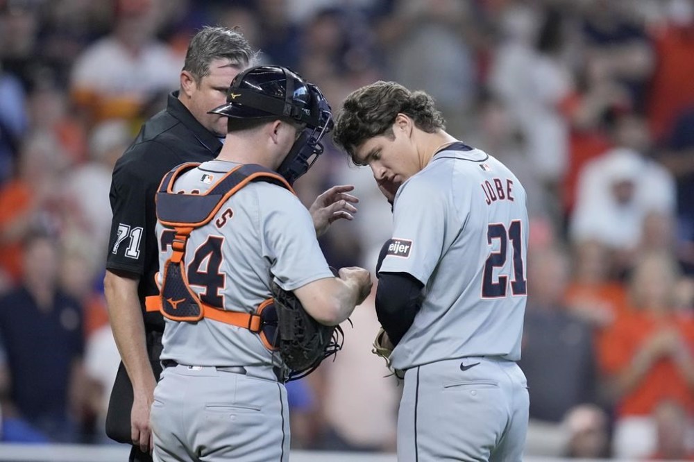 Detroit Tigers catcher Jake Rogers (34) and relief pitcher Jackson Jobe (21) work on Jobe's communications device as home plate umpire Jordan Baker (71) looks on in the seventh inning of Game 2 of an AL Wild Card Series baseball game Wednesday, Oct. 2, 2024, in Houston. (AP Photo/Kevin M. Cox)